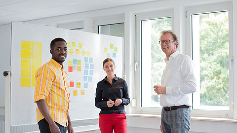 3 personen bij whiteboard die poseren